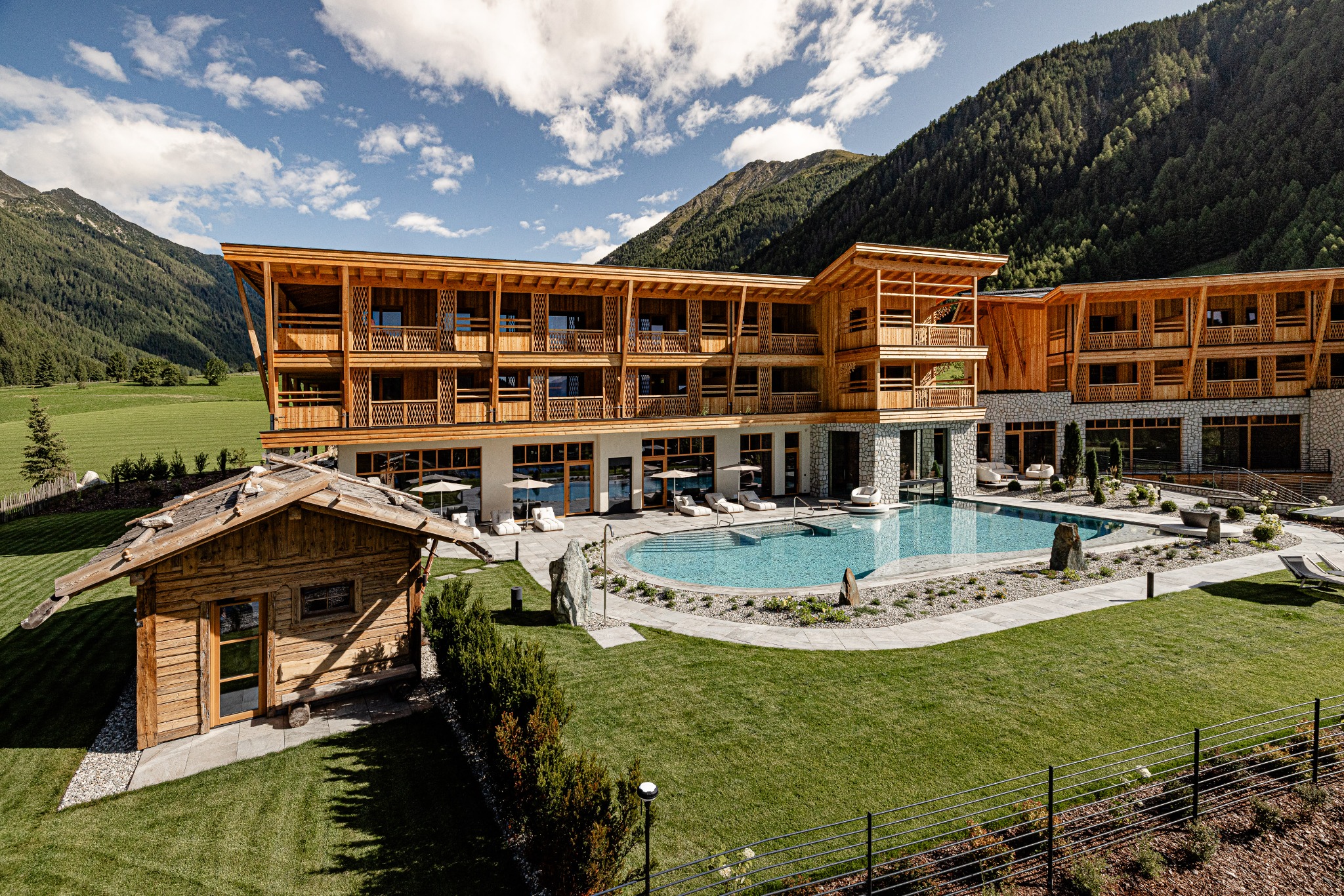 Hotel Masl mit Holzfassade, Berglandschaft und Außenpool